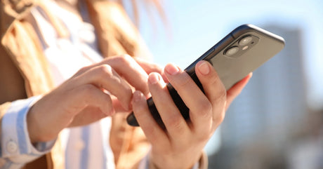  A close-up view shows a person holding a black iPhone in one hand and touching the screen with the other.
