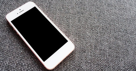 A close-up view shows the front and back of a black iPhone with a blank, white screen. It sits against a white background.